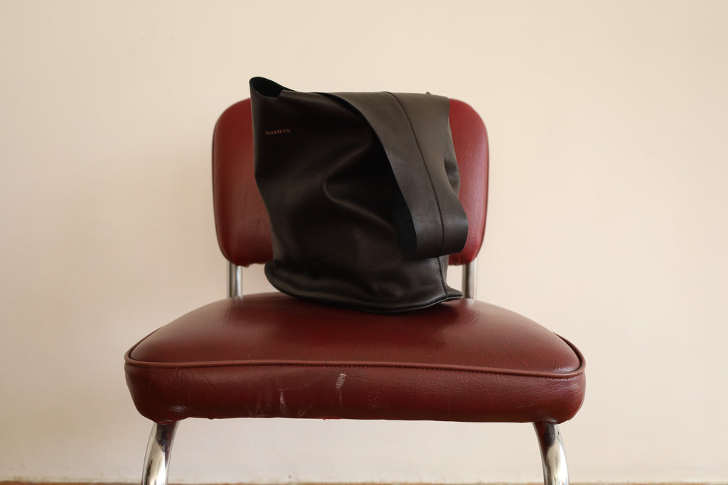 Black smooth leather Margarita Large handbag resting on a vintage chair.